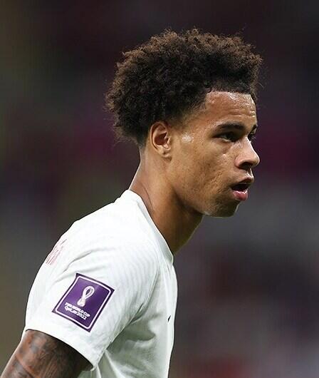 Tajon Buchanan in a white Canada jersey during the 2022 FIFA World Cup, focused and mid-match.