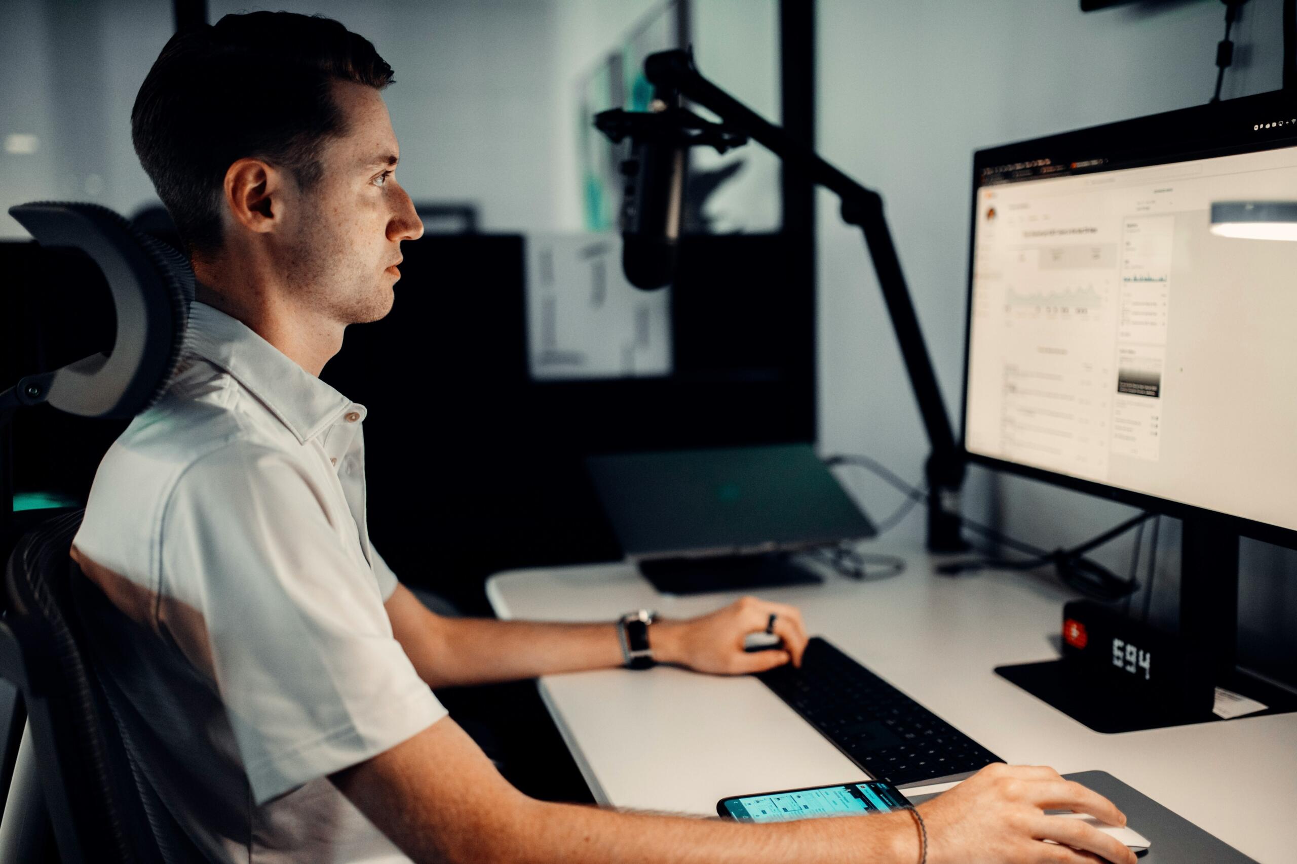 Sustainability analyst examining environmental performance data on a desktop monitor in a modern office workspace.