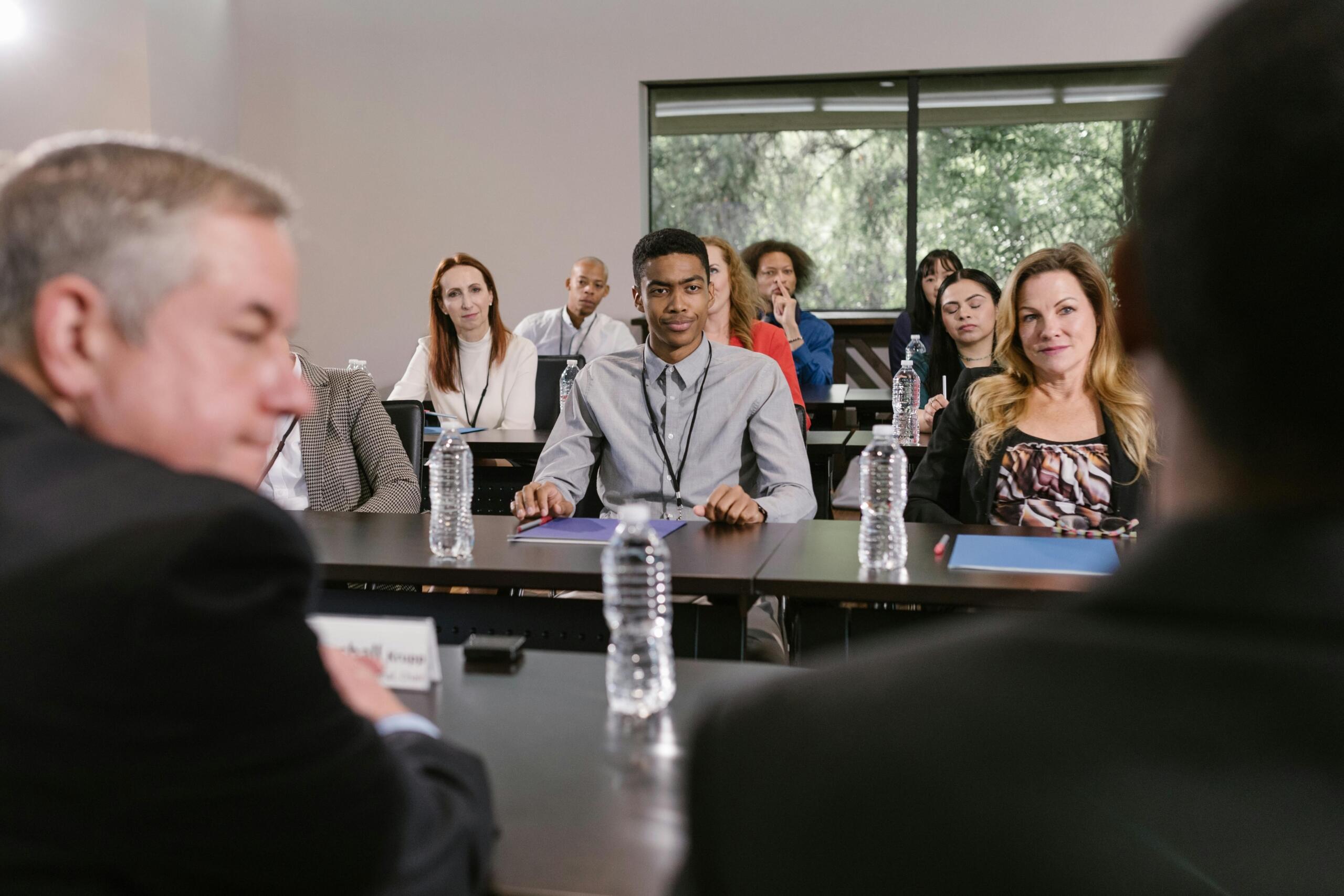A diverse group of students and professionals attentively listening in a classroom or seminar setting, symbolizing modern business education and collaborative learning.