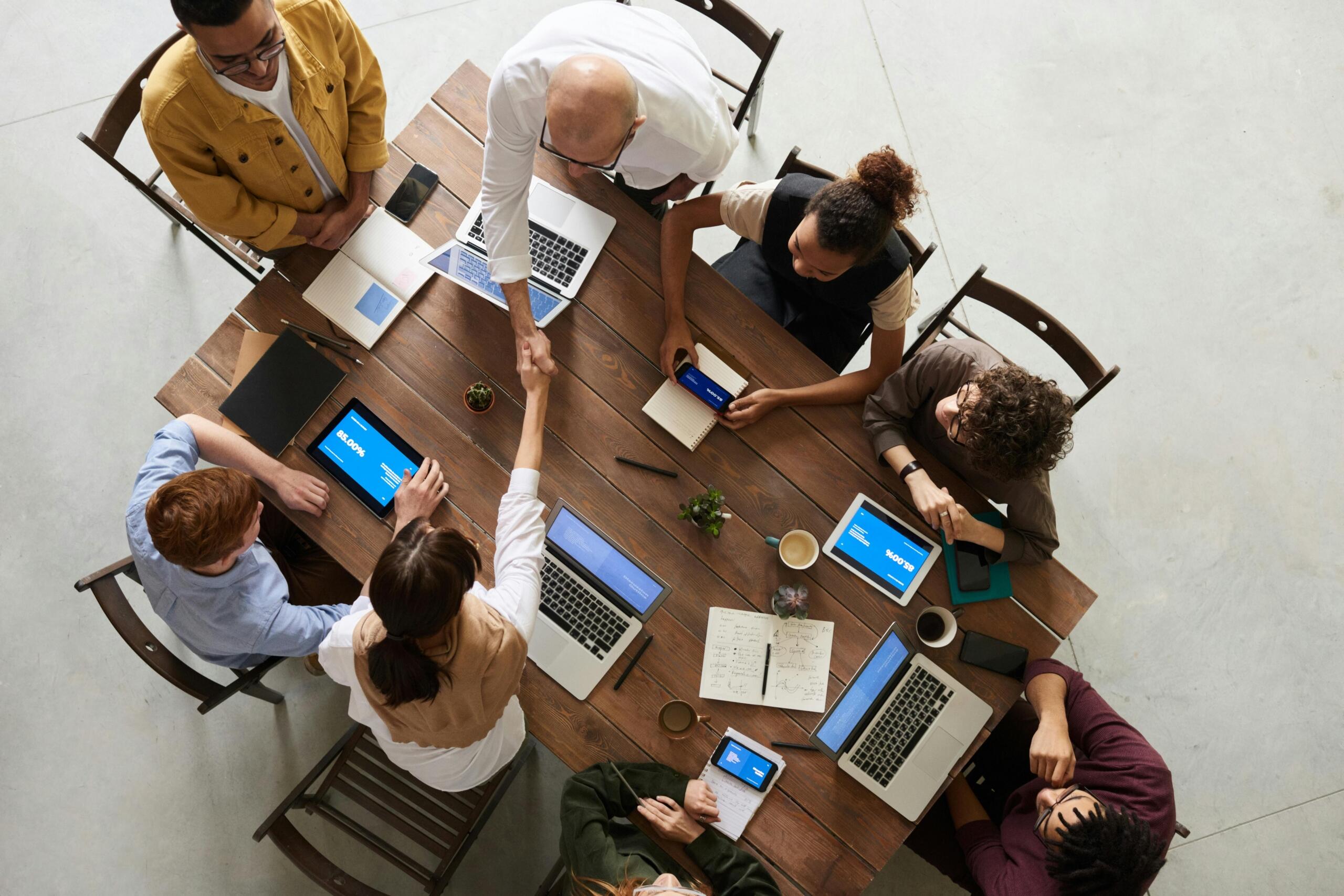 A diverse group of professionals collaborating around a wooden conference table, representing inclusive workplace practices and ethical decision-making.