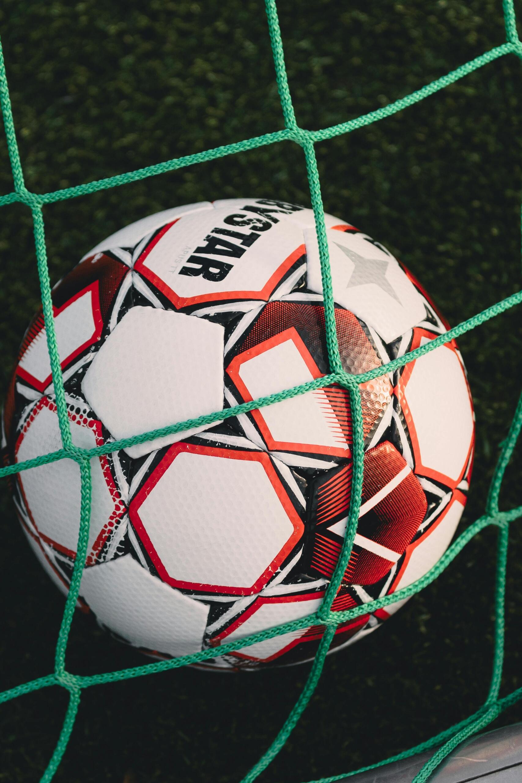  A soccer ball caught in the back of the net, nestled against the white mesh, symbolizing a successful goal.