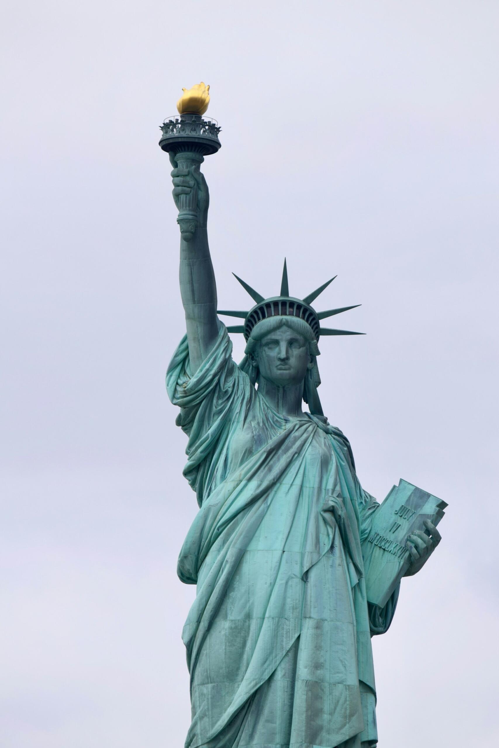 The Statue of Liberty stands tall, holding a torch aloft, symbolizing freedom and welcoming visitors to New York Harbor.