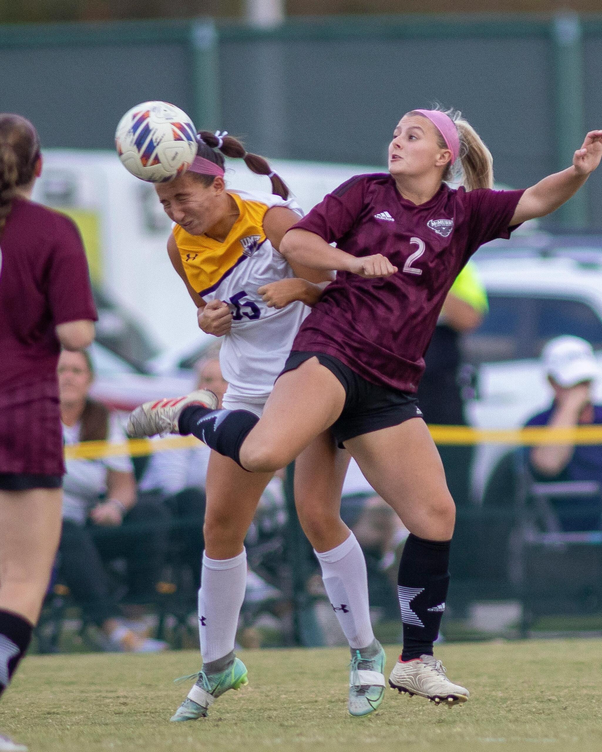 Action shot of a women's soccer game, with players focused on the ball, and teammates positioned for passes or defense.