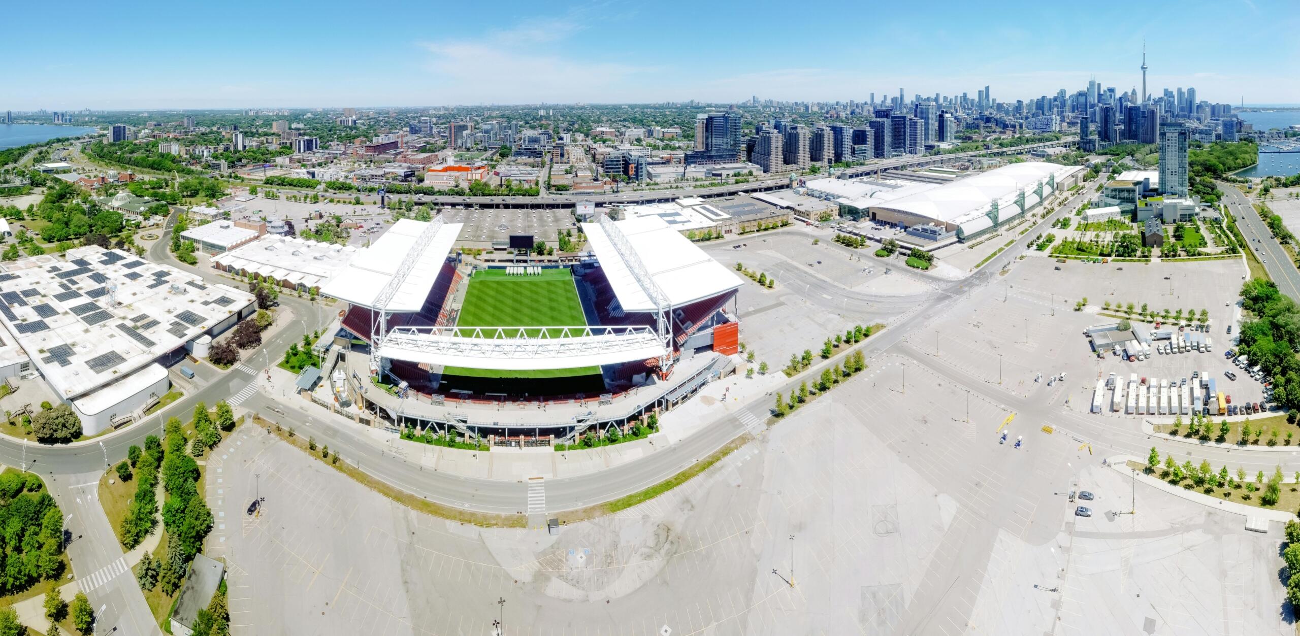 Aerial view of a soccer stadium in Toronto, with the city skyline in the background and the green pitch clearly visible inside the oval-shaped structure. 