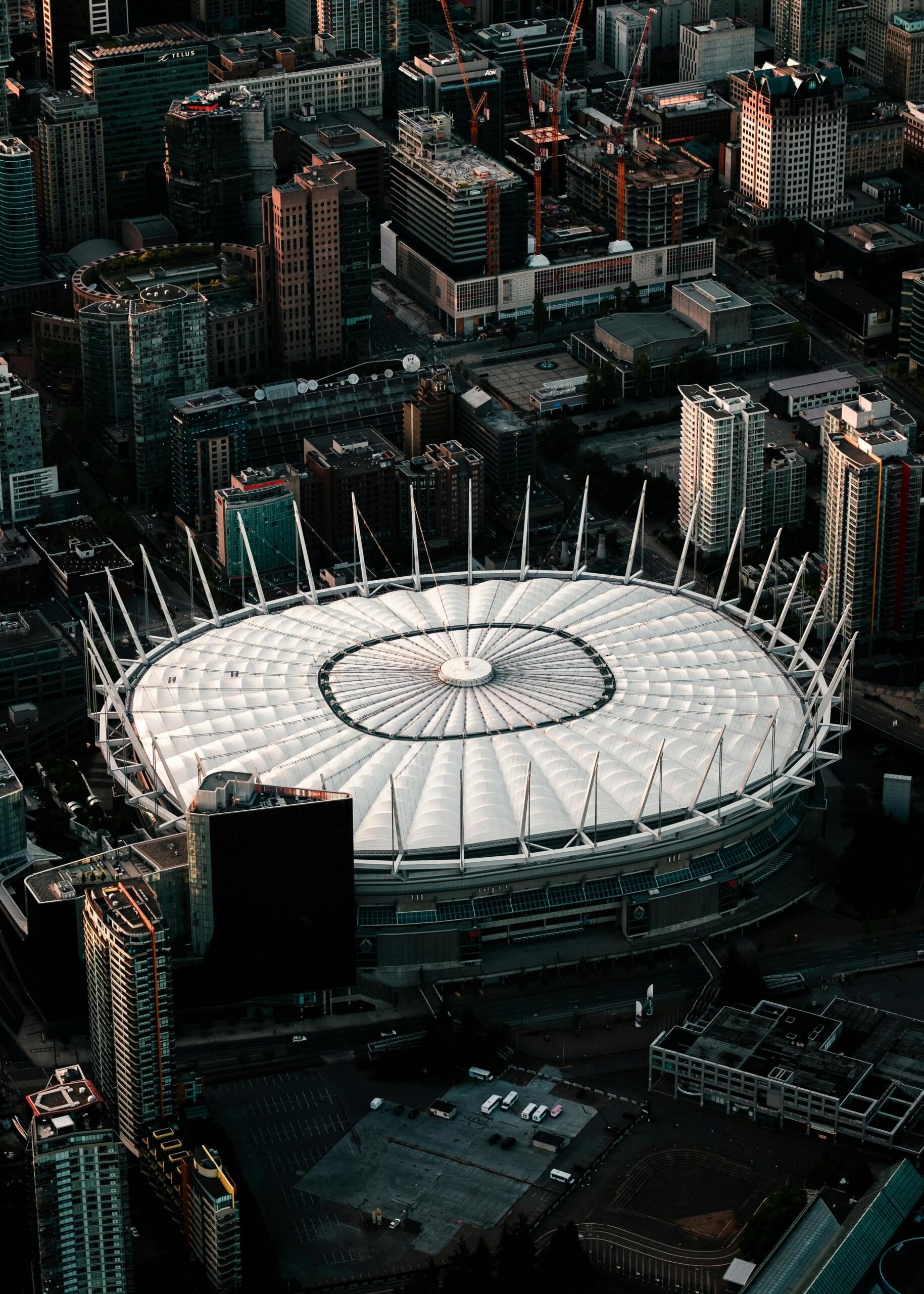 An aerial view of a stadium in Vancouver, showcasing the stands, field, and surrounding cityscape with towering buildings in the background.