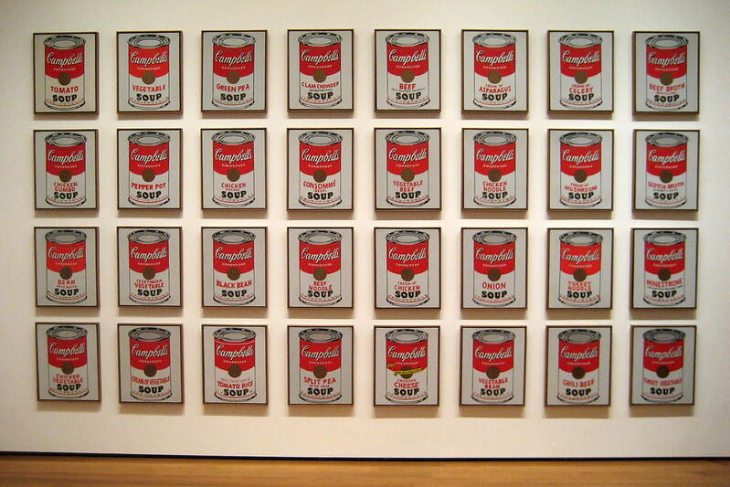 A grid of 32 framed Campbell's Soup can artworks, each featuring different soup varieties with bold red and white designs.