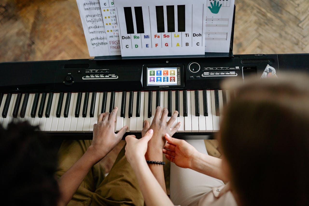 A child and an instructor play the keyboard together, with music sheets and a digital screen displaying music notes and instructions.