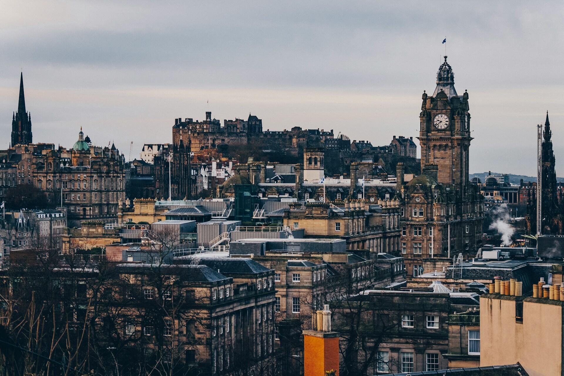 A panoramic view of Edinburgh showcasing historic architecture, including the iconic clock tower and Edinburgh Castle in the background.