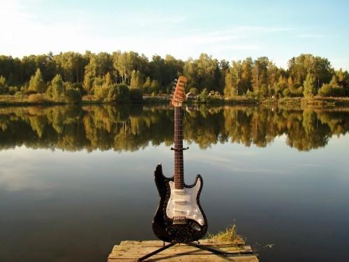 An electric guitar against a lake.