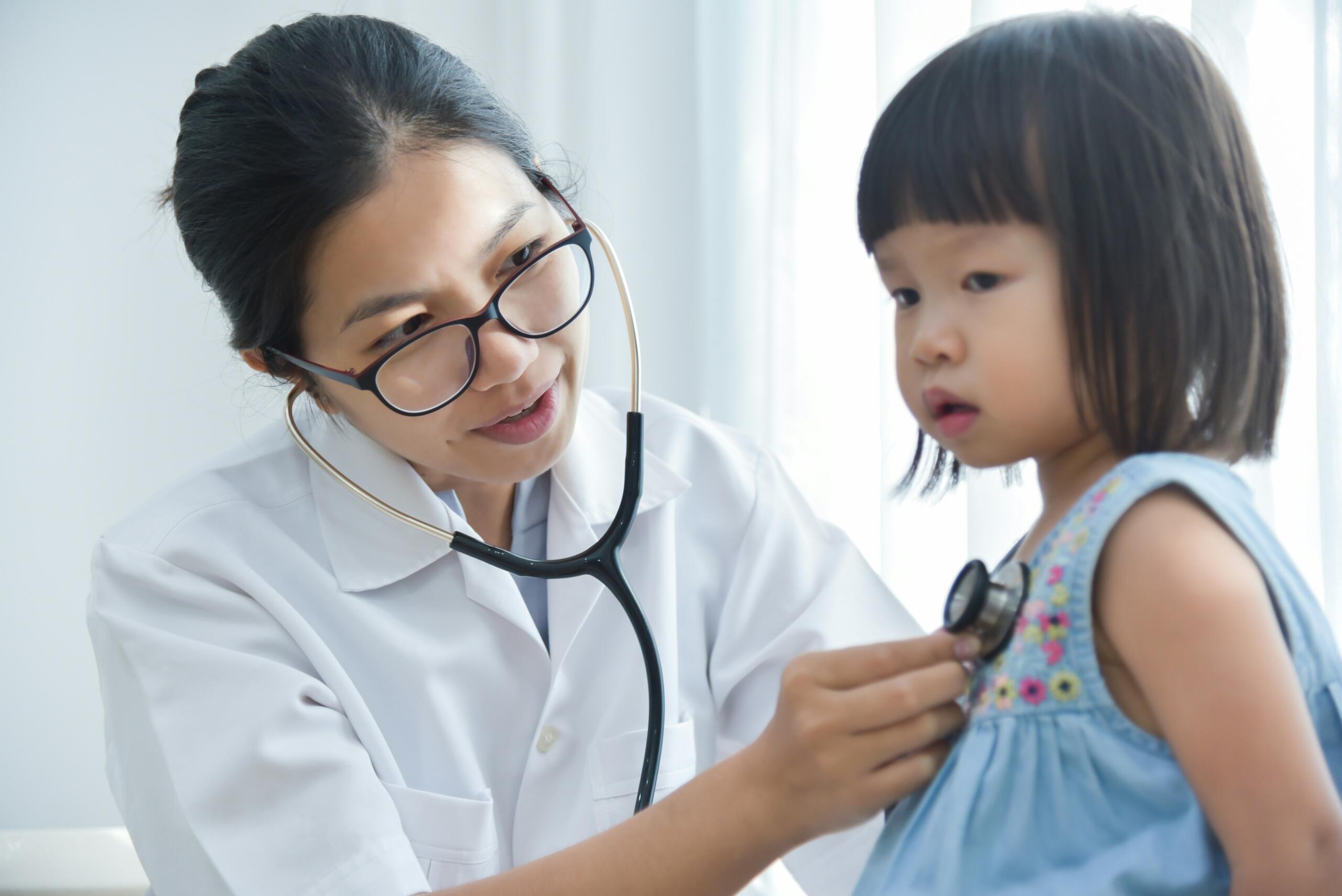 female nurse listening to heartbeat of a young child