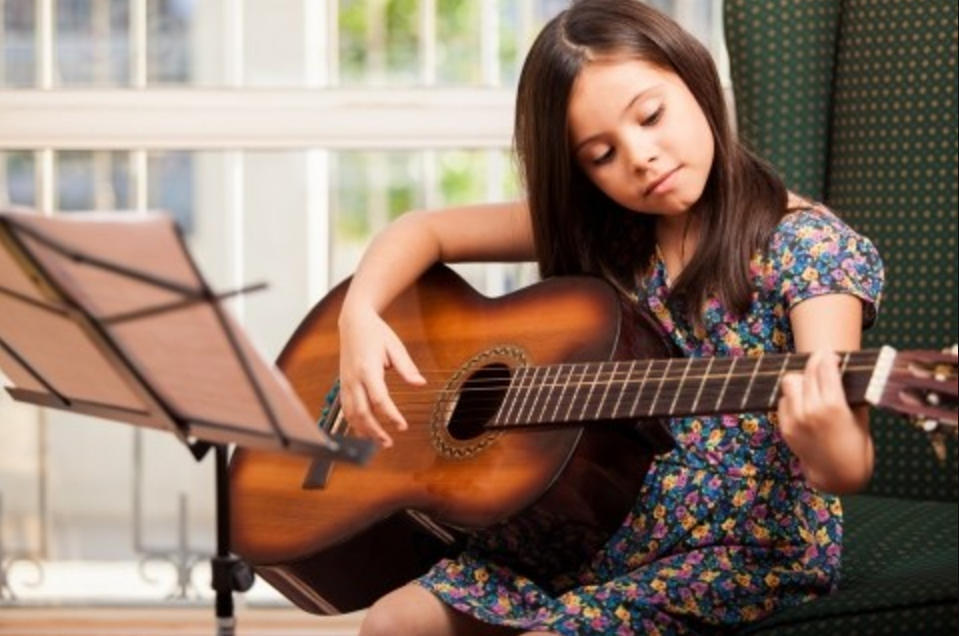 A young girl practicing her guitar playing and chords.
