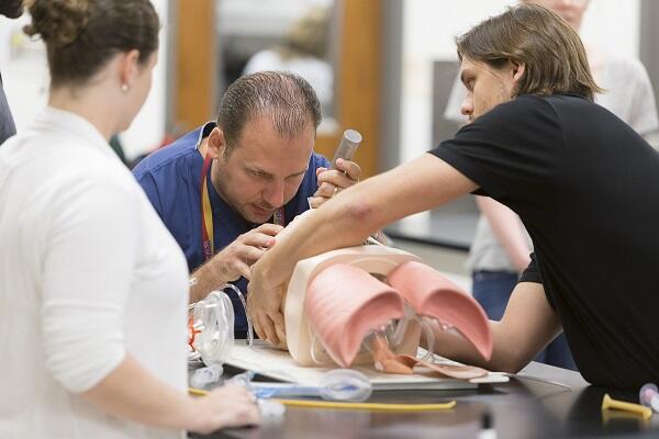 Medical students practicing intubation skills on a simulated patient model during clinical training.