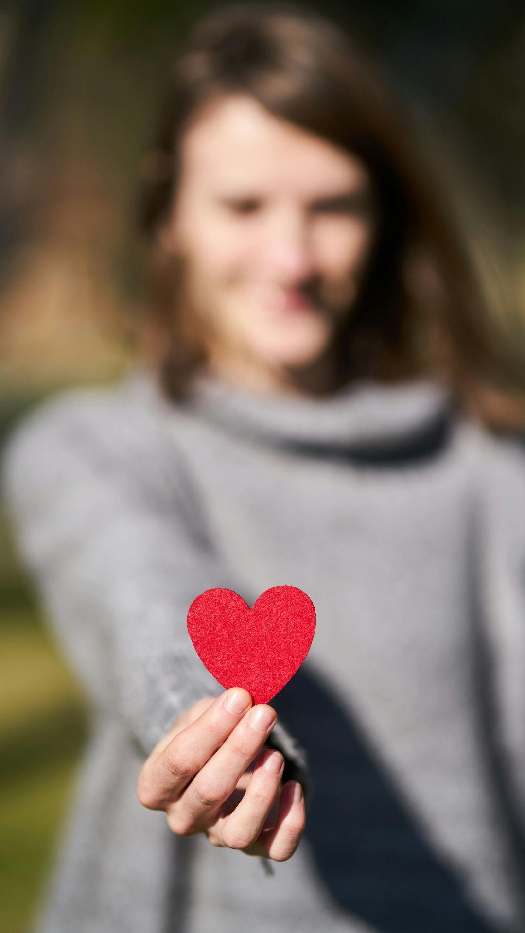 Person holding a red heart symbol to represent cardiology and heart health.