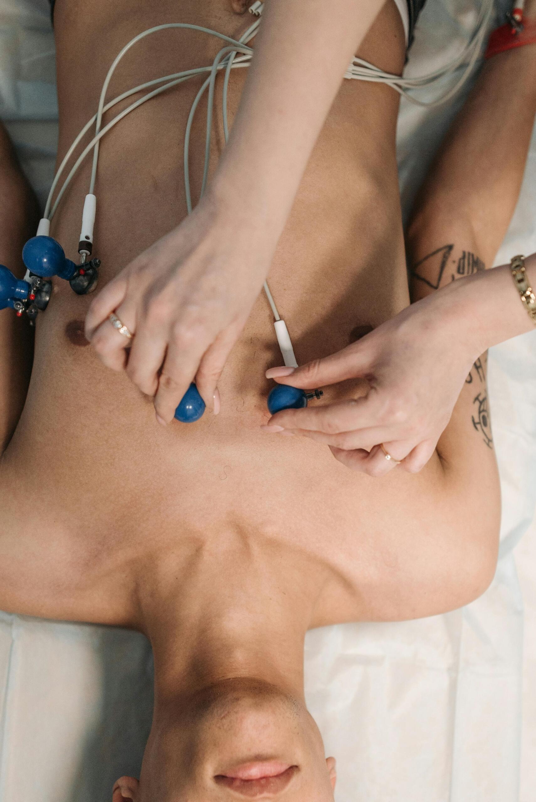 Cardiologist examining a patient’s chest with medical equipment for heart monitoring.