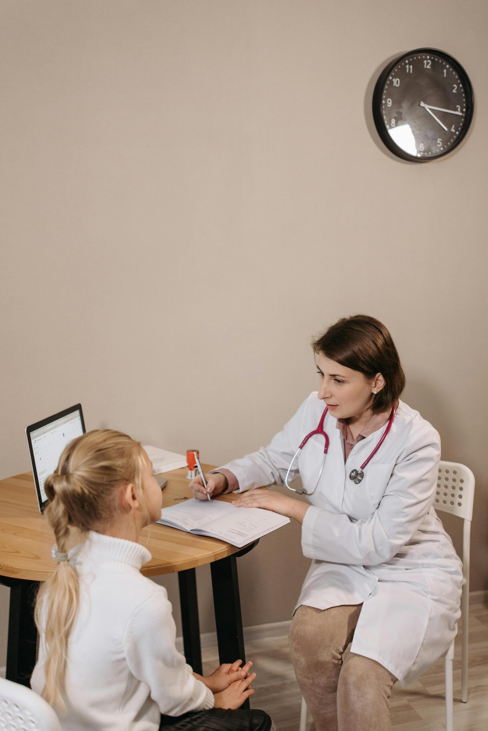 Doctor in a white coat consulting a young girl during a family medicine appointment.
