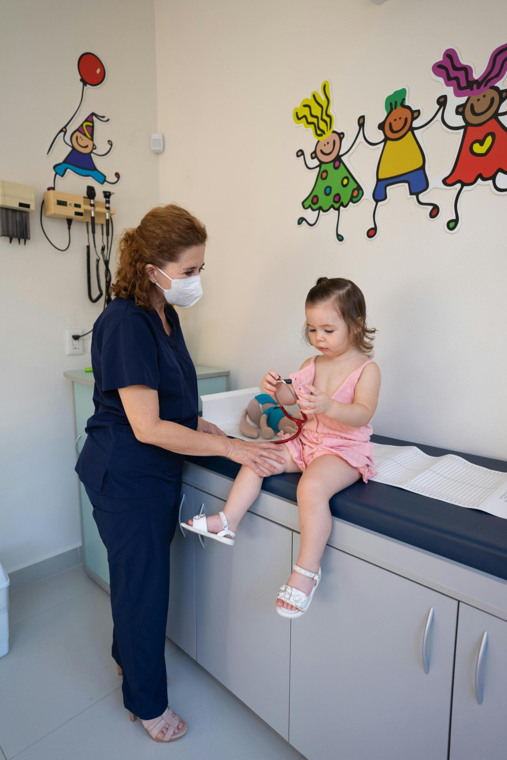 Pediatrician examining a young child in a clinic.