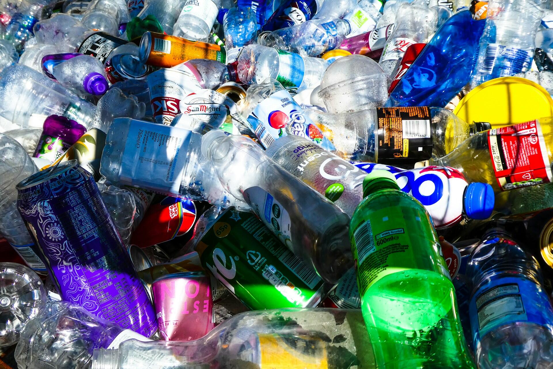 A chaotic pile of assorted plastic bottles, cans, and containers in various colors, illustrating waste accumulation.