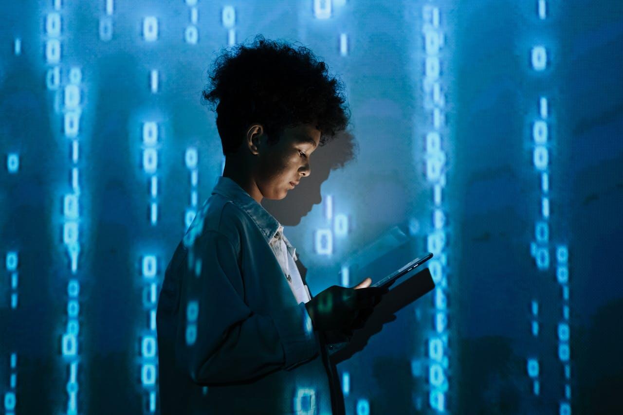 A child holds a device, illuminated by a blue digital backdrop displaying binary code, creating a tech-inspired atmosphere.