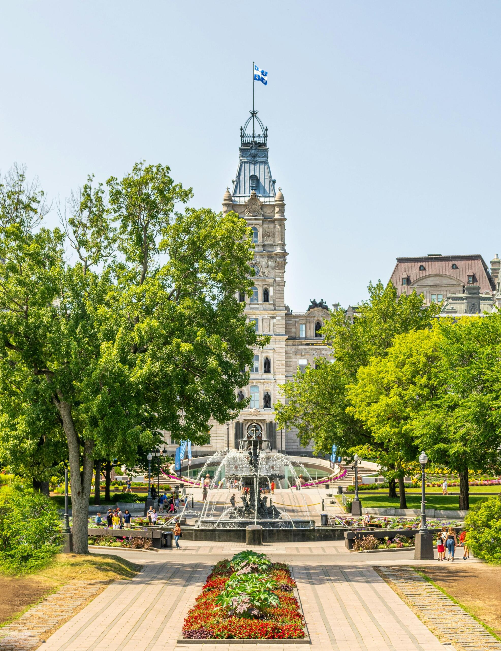The government building in Quebec city, surrounded by trees and walkways, on a sunny day.
