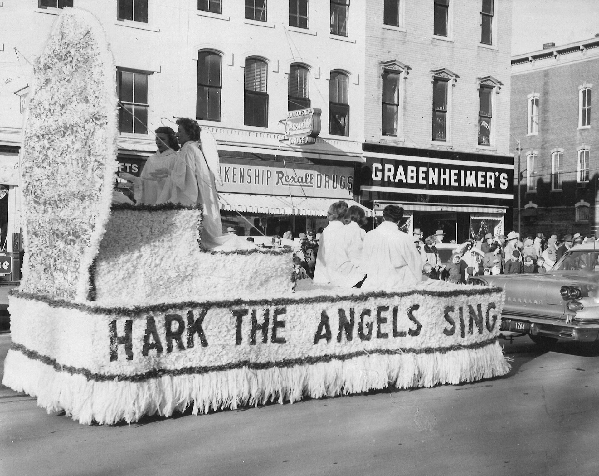 A festive parade float adorned with flowers features the phrase