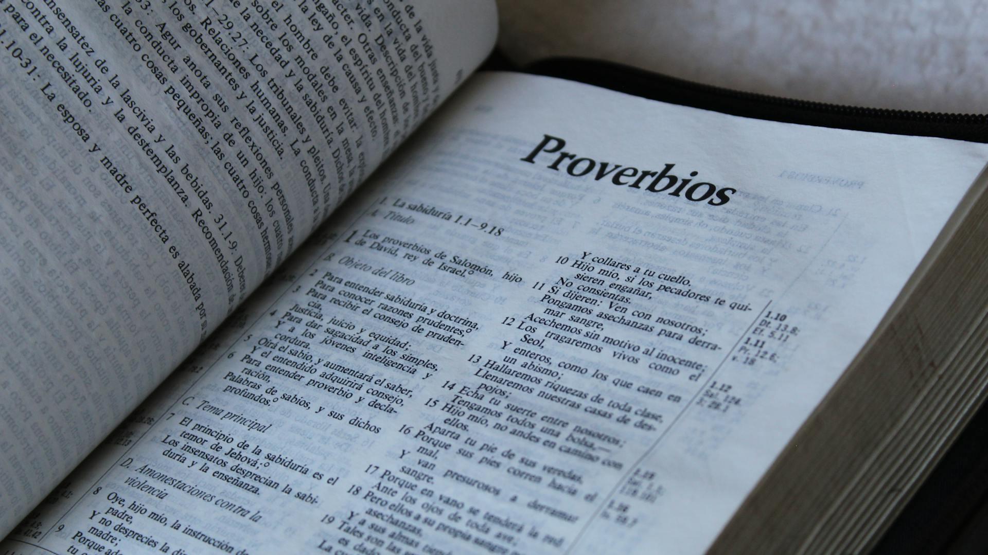 An open Bible displaying the book of "Proverbios" (Proverbs) in Spanish, with text on wisdom and guidance.