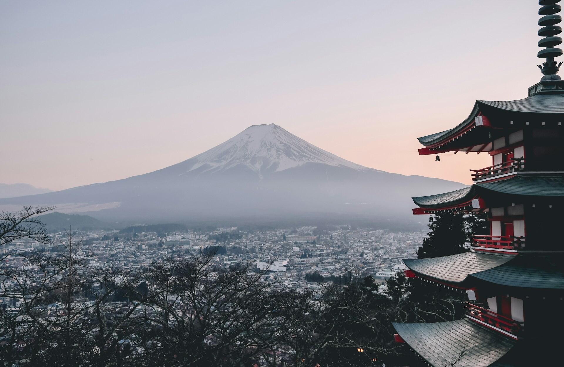 A serene view of Mount Fuji in the background, with a traditional pagoda in the foreground against a soft pastel sky.