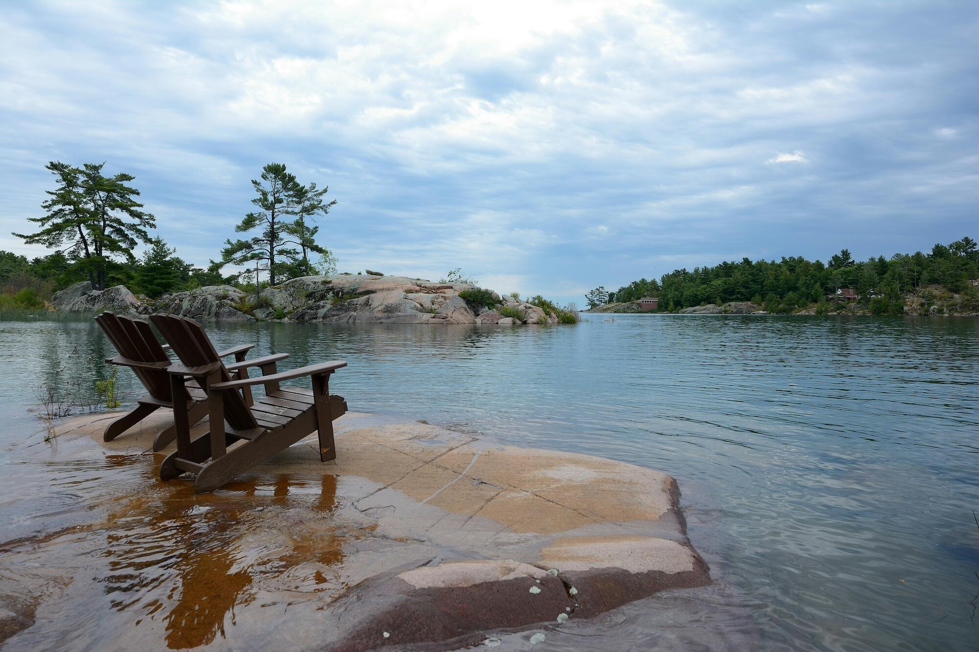 A serene lake reflects a stunning sunset, with trees lining the shore and a sky filled with warm, glowing colors.