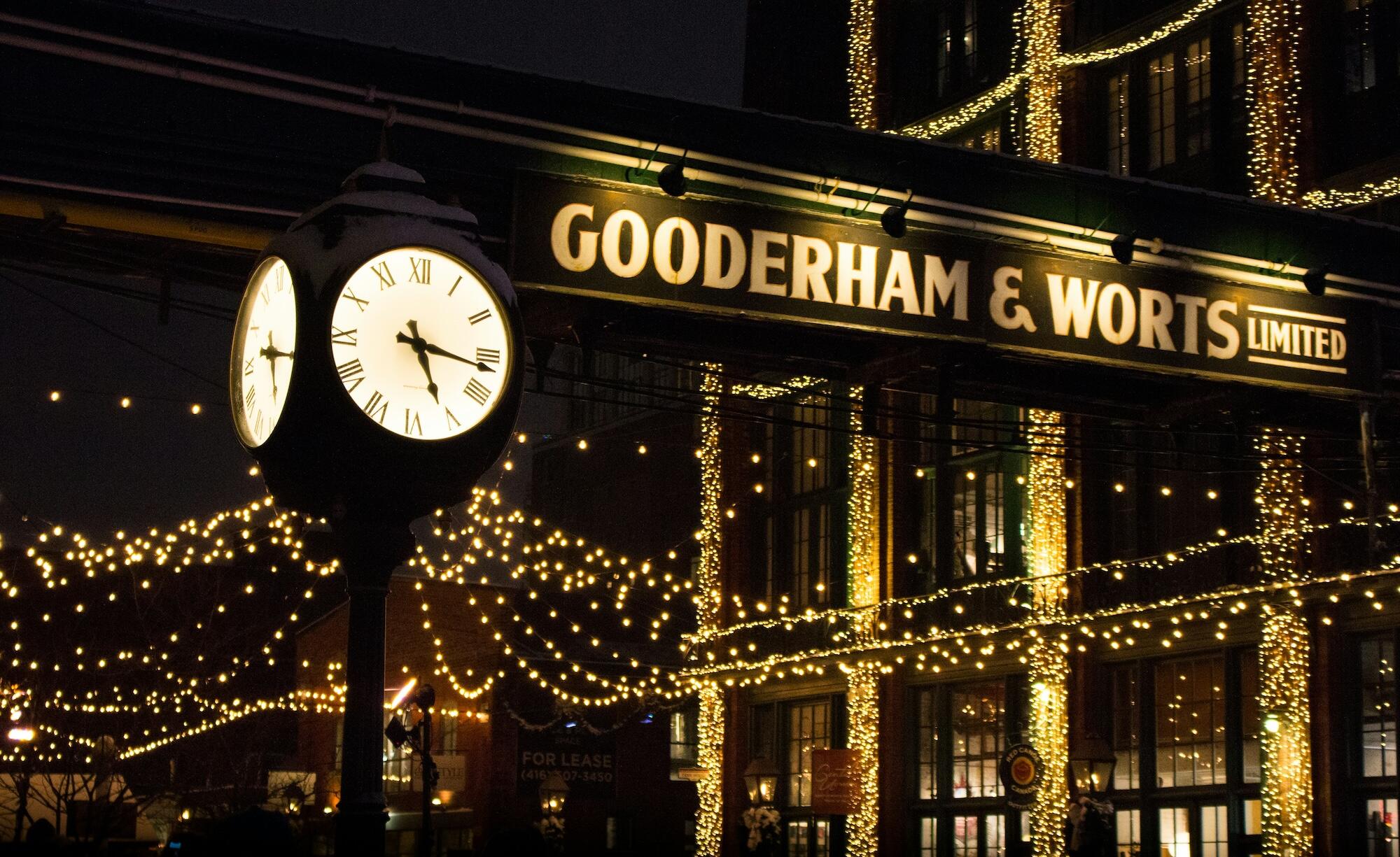 A clock on a building, beautifully illuminated by surrounding lights, enhancing the nighttime view.