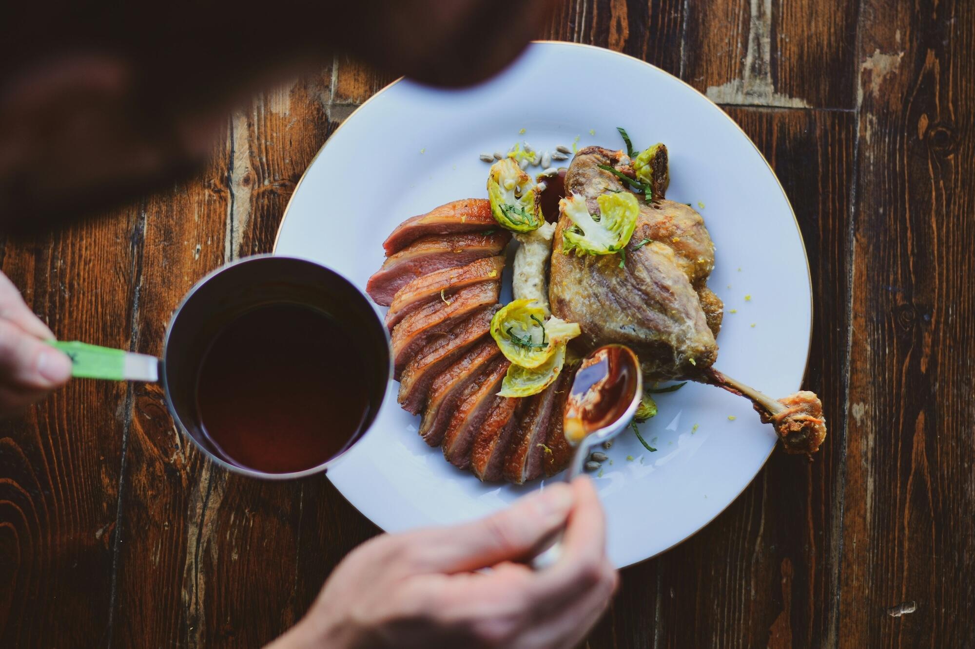 A man holds a spoon, savoring a piece of meat as he eats.