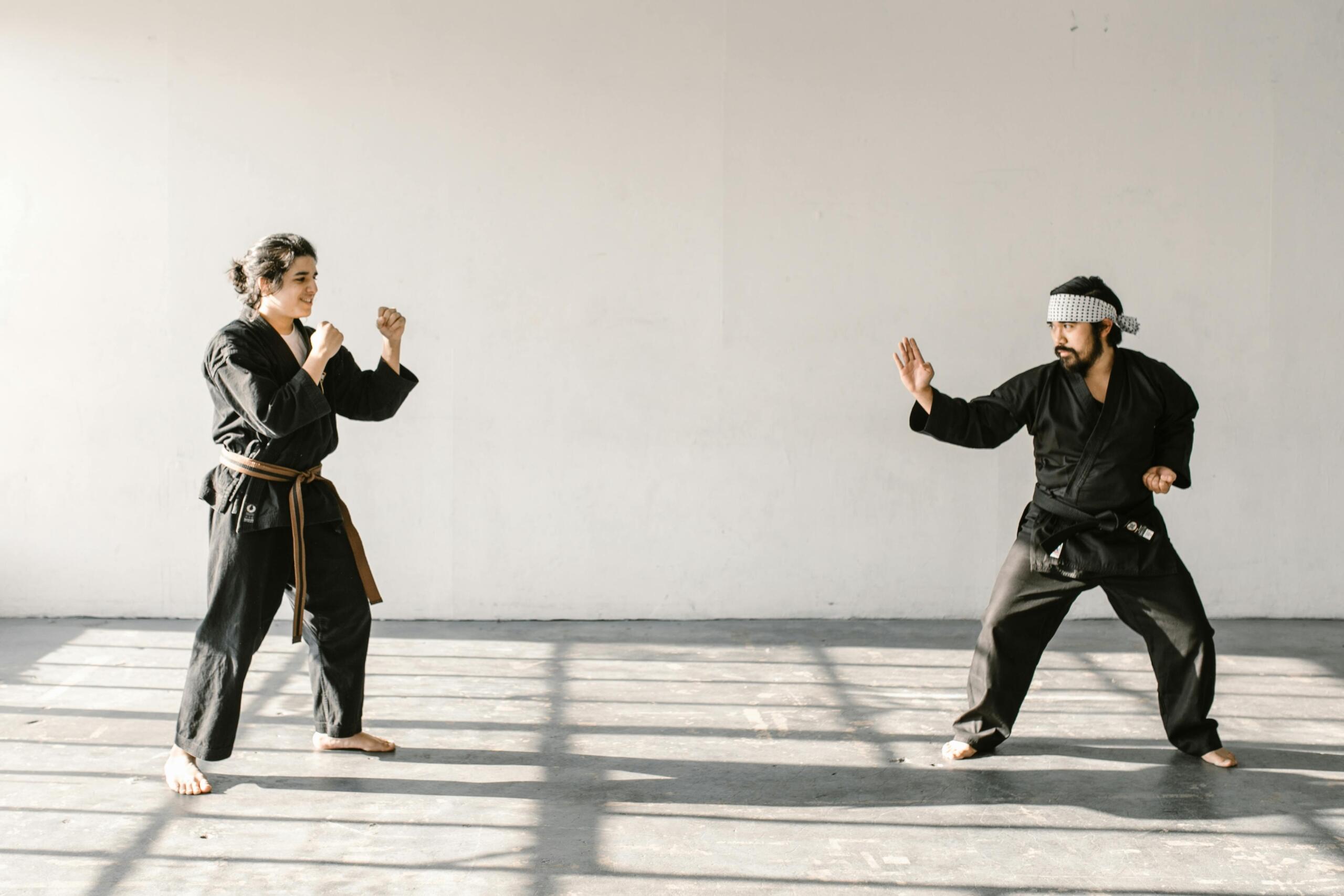 Two Taekwondo fighters standing across from each other on a competition mat, facing off before a match begins.
