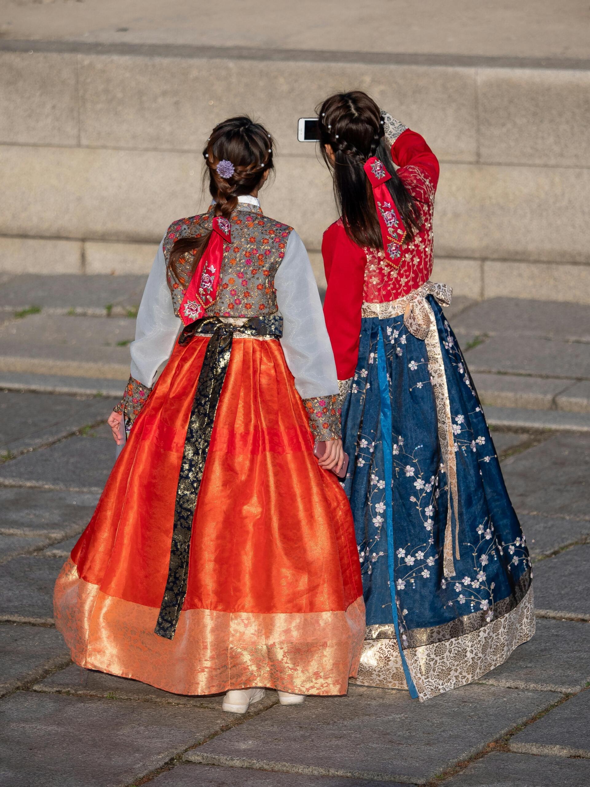 Two women wearing colourful hanbok taking a photo together during a Korean cultural event.
