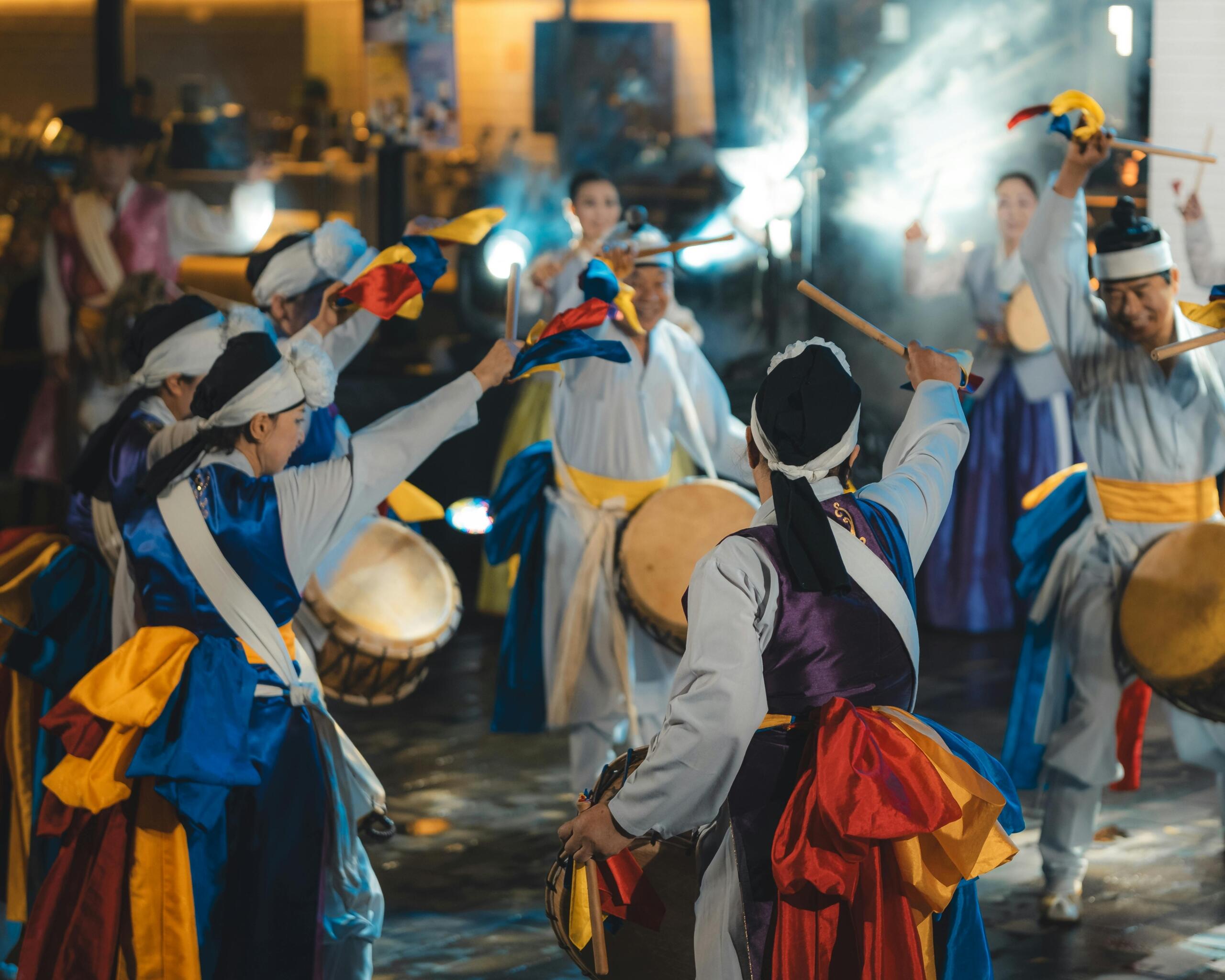 Traditional Korean drummers performing in ceremonial attire, playing large drums during a cultural festival performance.