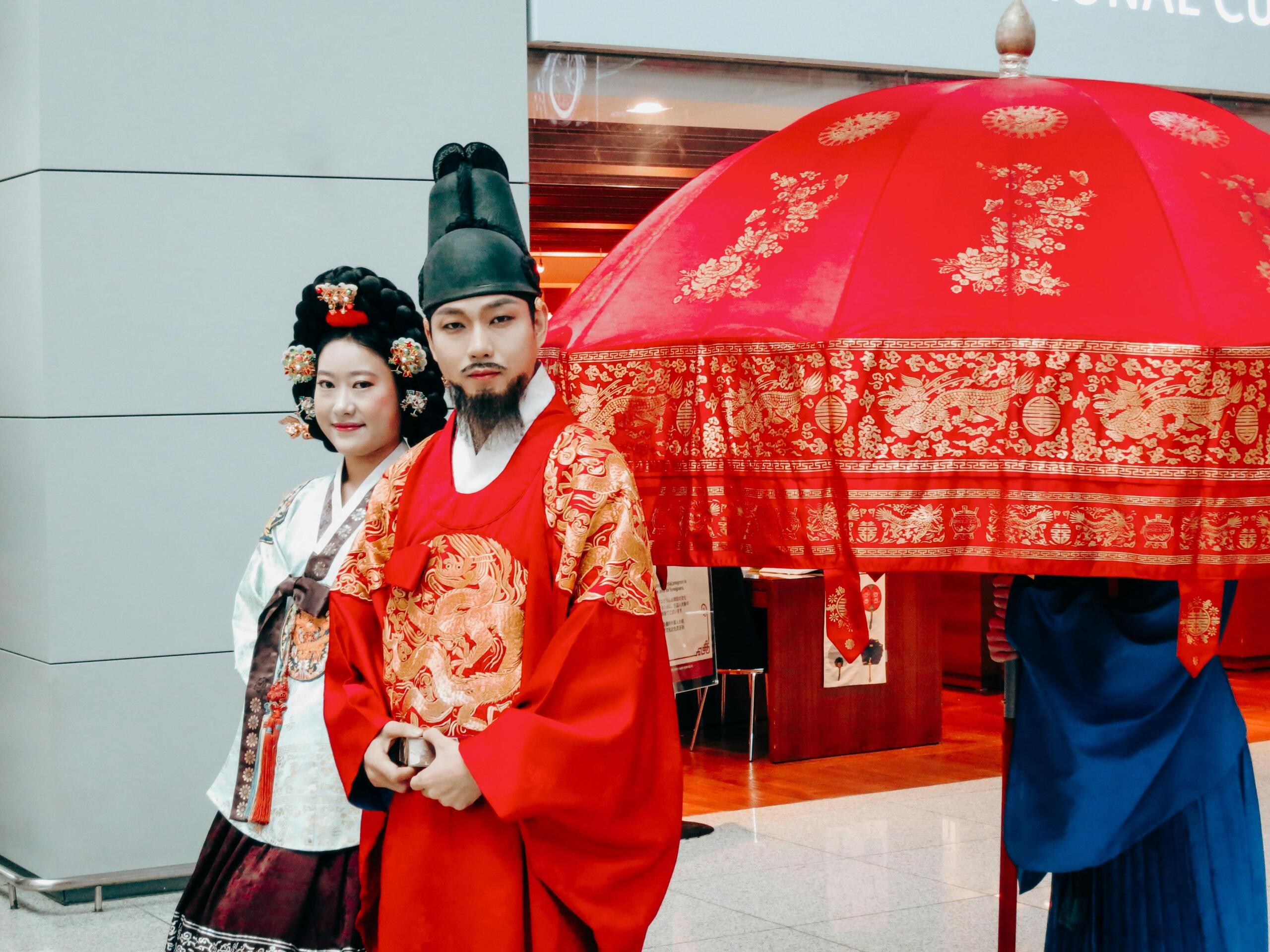 Korean man and woman wearing traditional dress, walking together in a cultural procession during a festival.