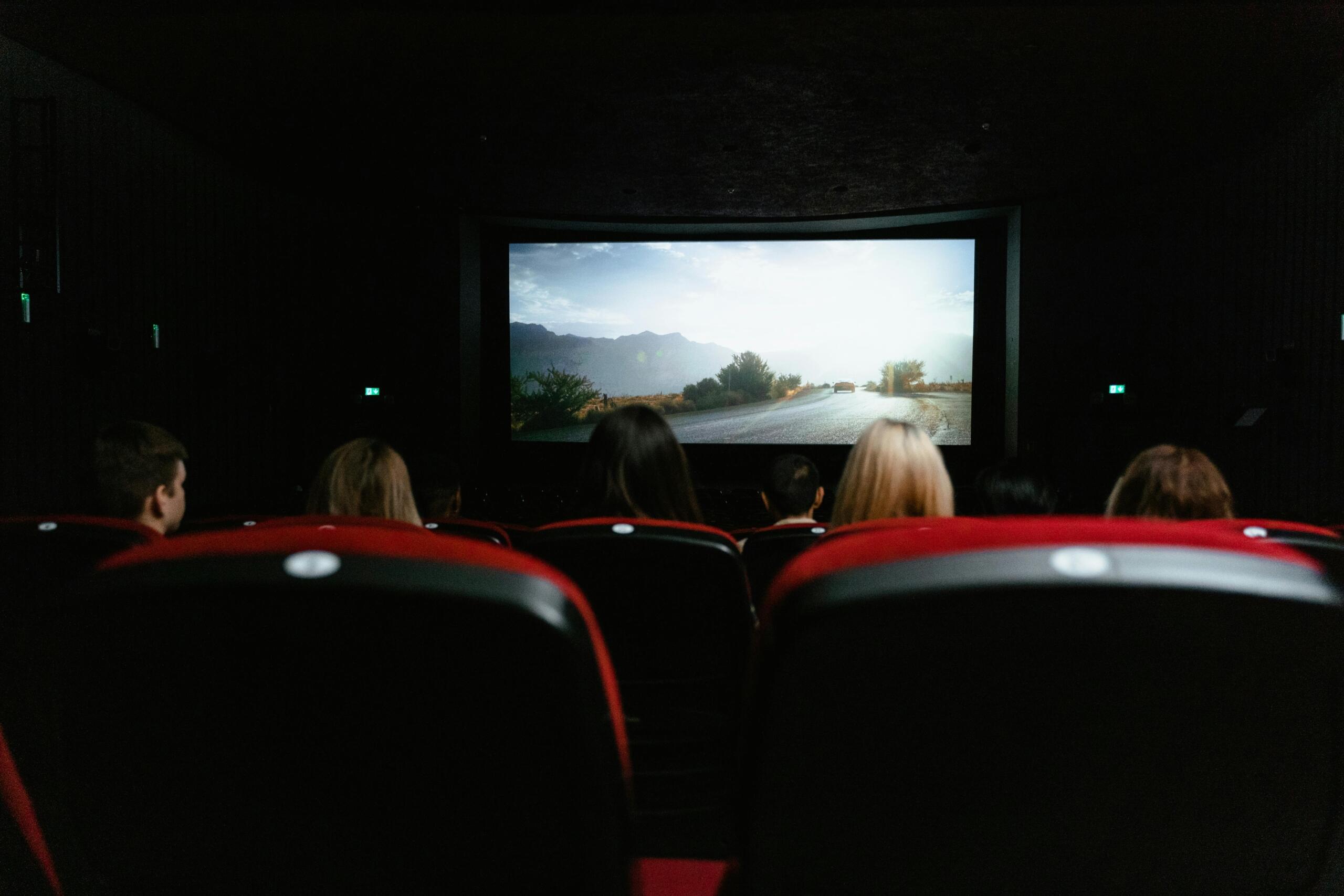 People seated in a movie theatre, watching a film together in a darkened auditorium.
