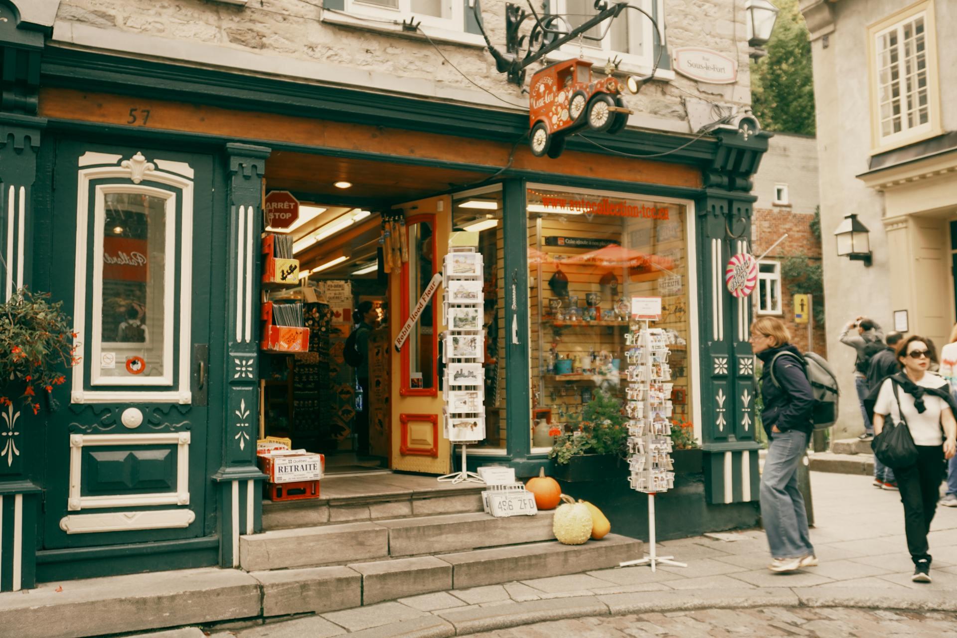 Charming storefront with colorful signage, displays of souvenirs, and decorative pumpkins, set in a quaint cobblestone street.