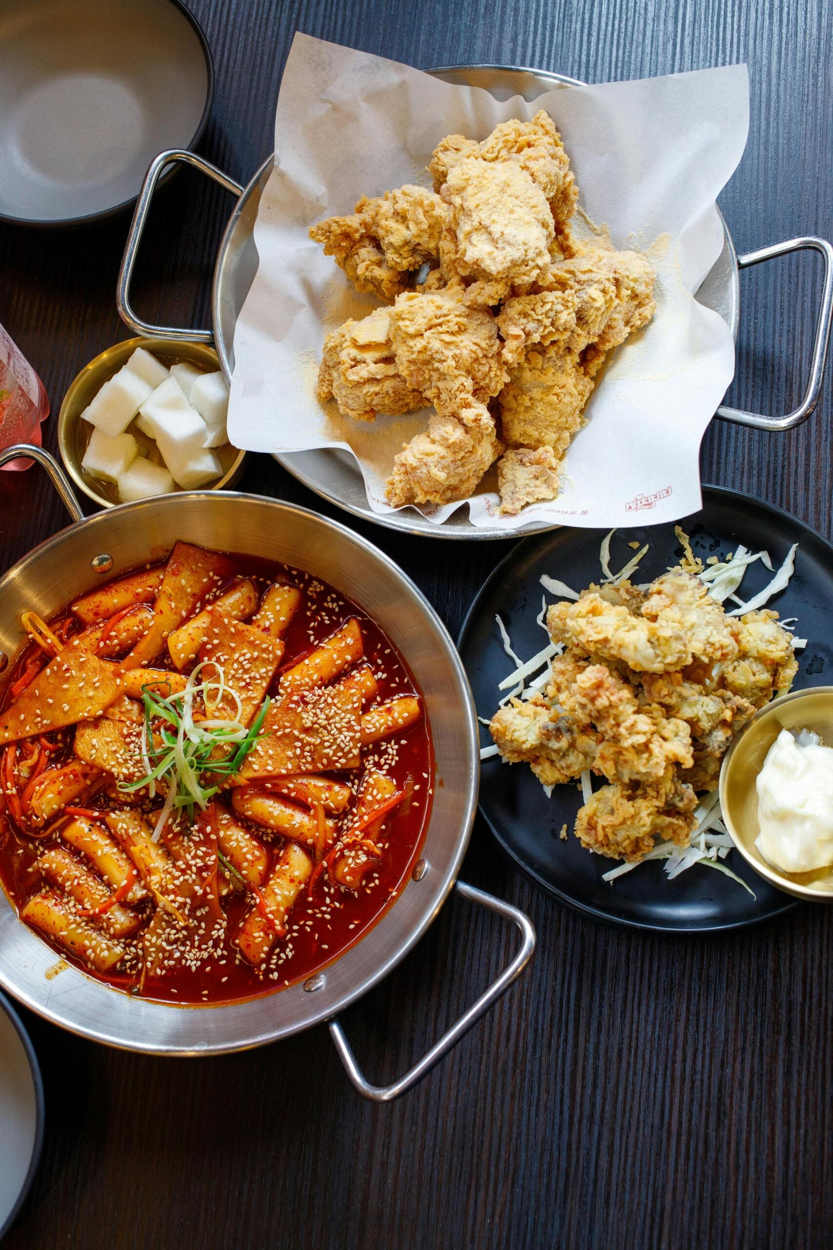 Korean street food featuring spicy tteokbokki and crispy fried chicken served together, highlighting popular Korean comfort dishes.