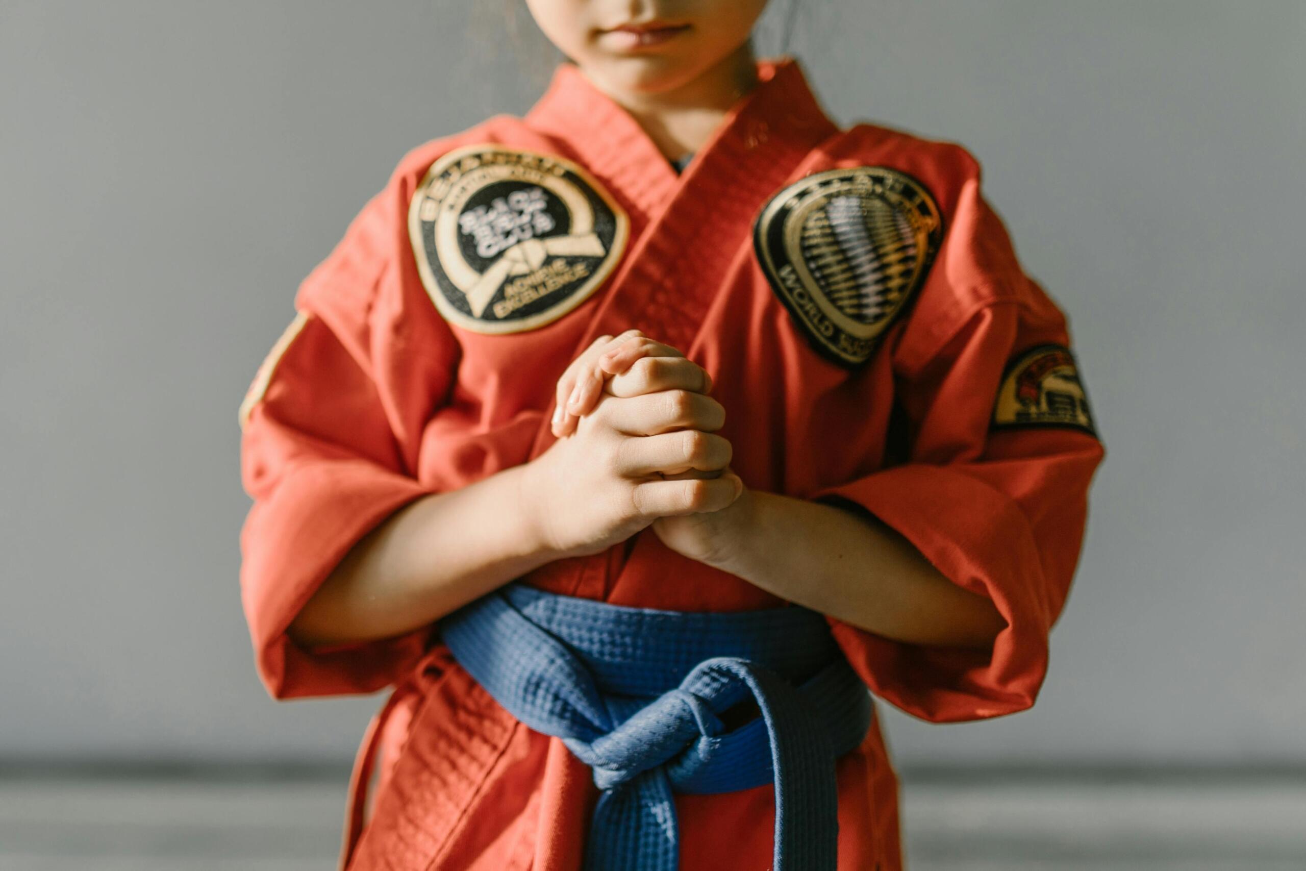 Boy competing in a Taekwondo tournament, wearing a red uniform and in a focused stance.