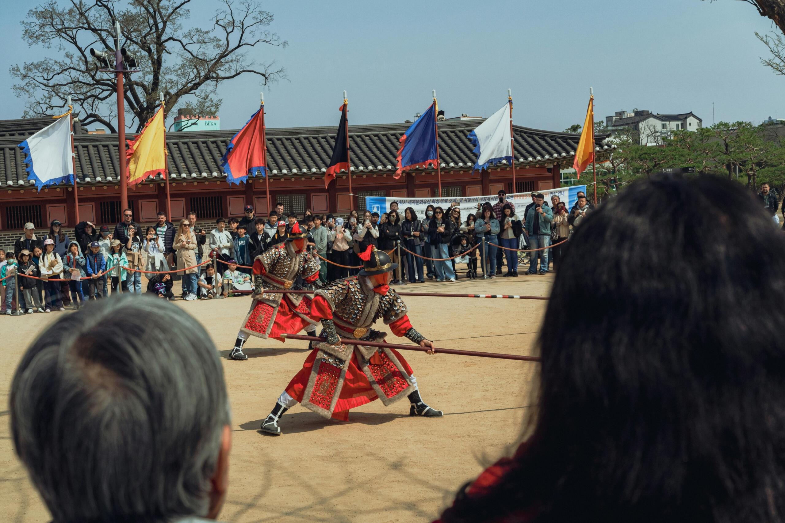 Koreans wearing traditional cultural dress demonstrating ancient combat techniques during a historical reenactment.