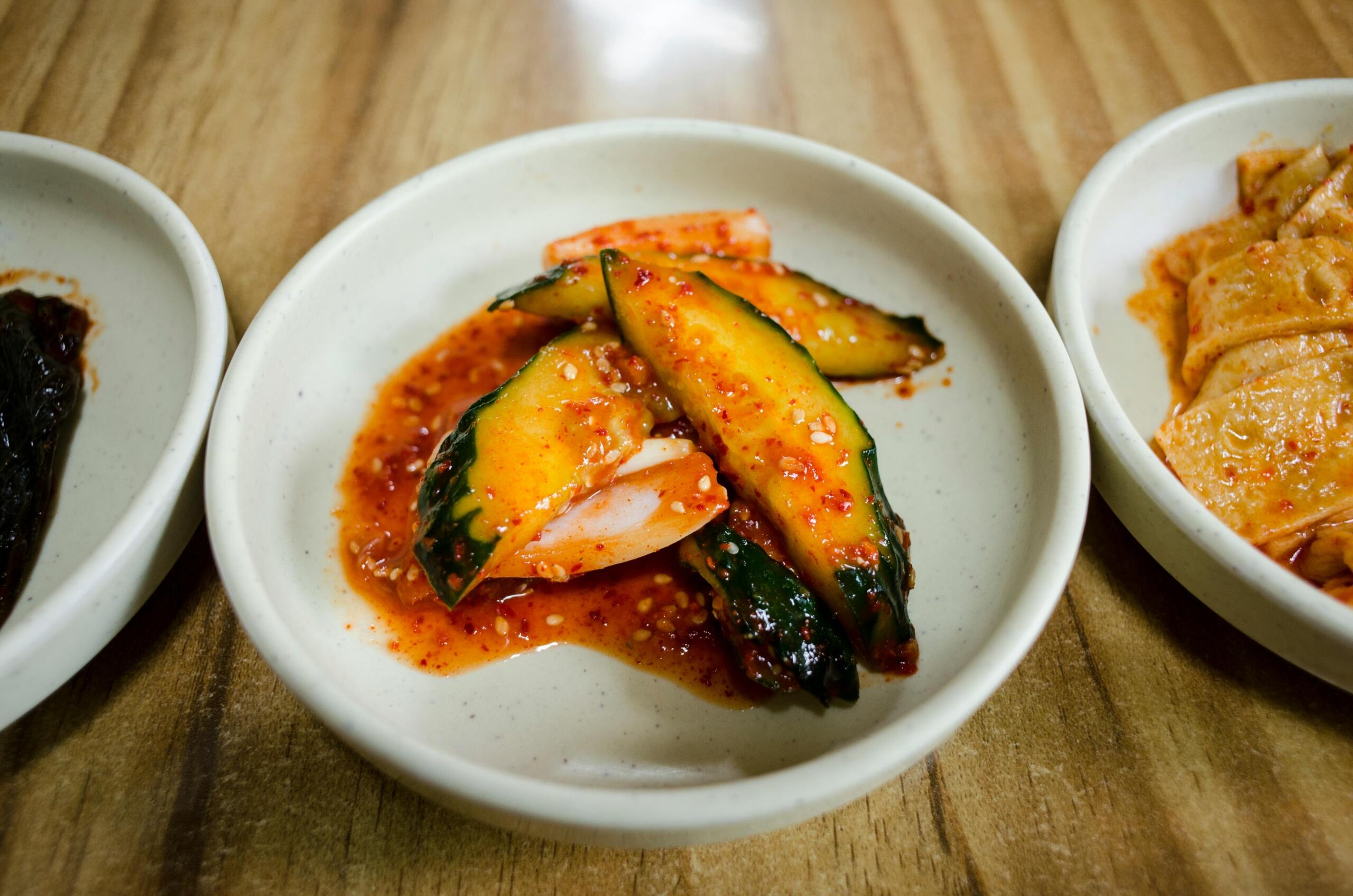 Plates of banchan, featuring a variety of small Korean side dishes such as kimchi, pickled vegetables, and seasoned greens.