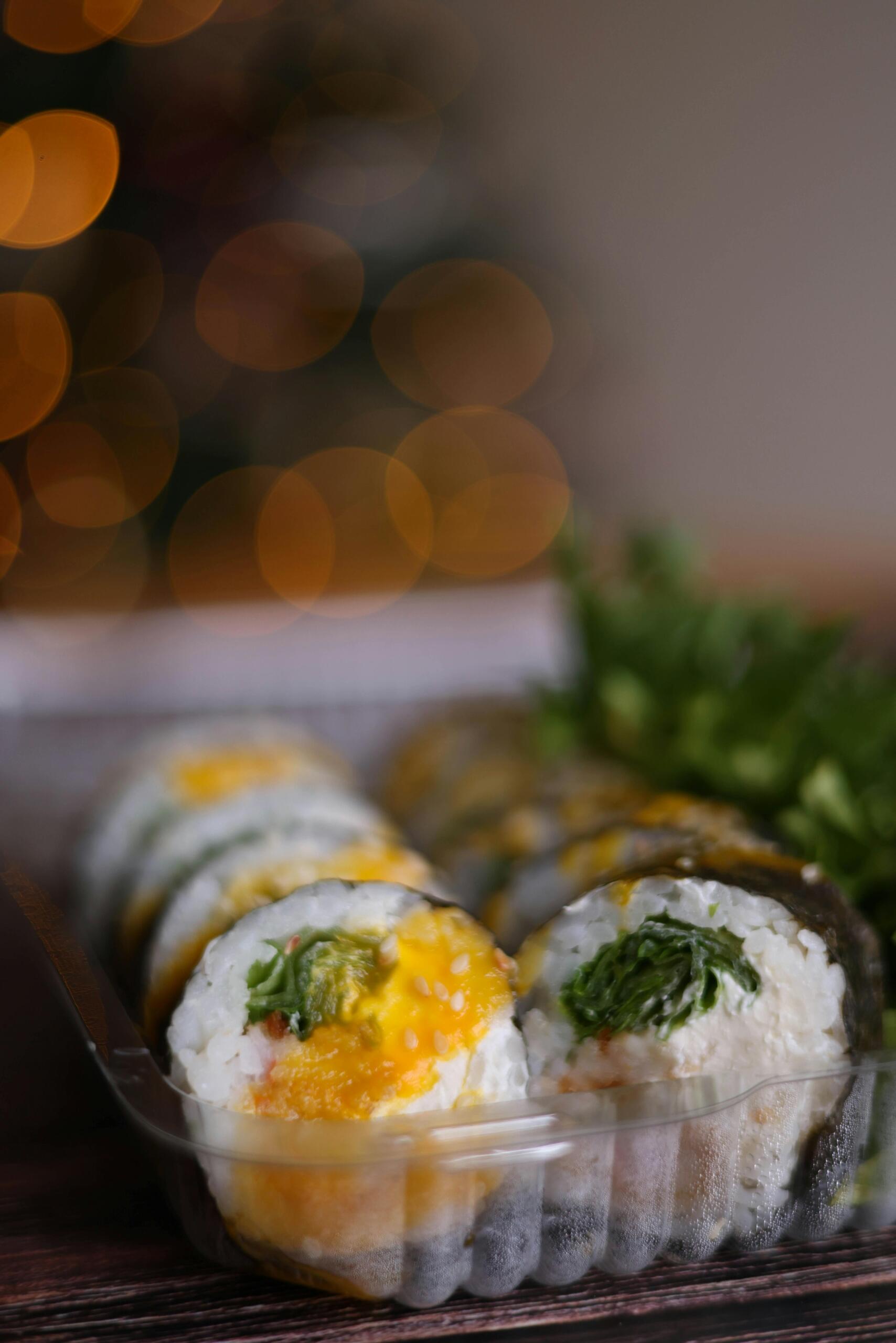 Kimbap neatly arranged in a takeout container, showing sliced rolls filled with vegetables and rice.