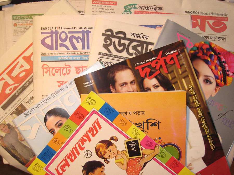 A collection of Bengali newspapers and magazines, featuring colorful covers and diverse topics, stacked together.