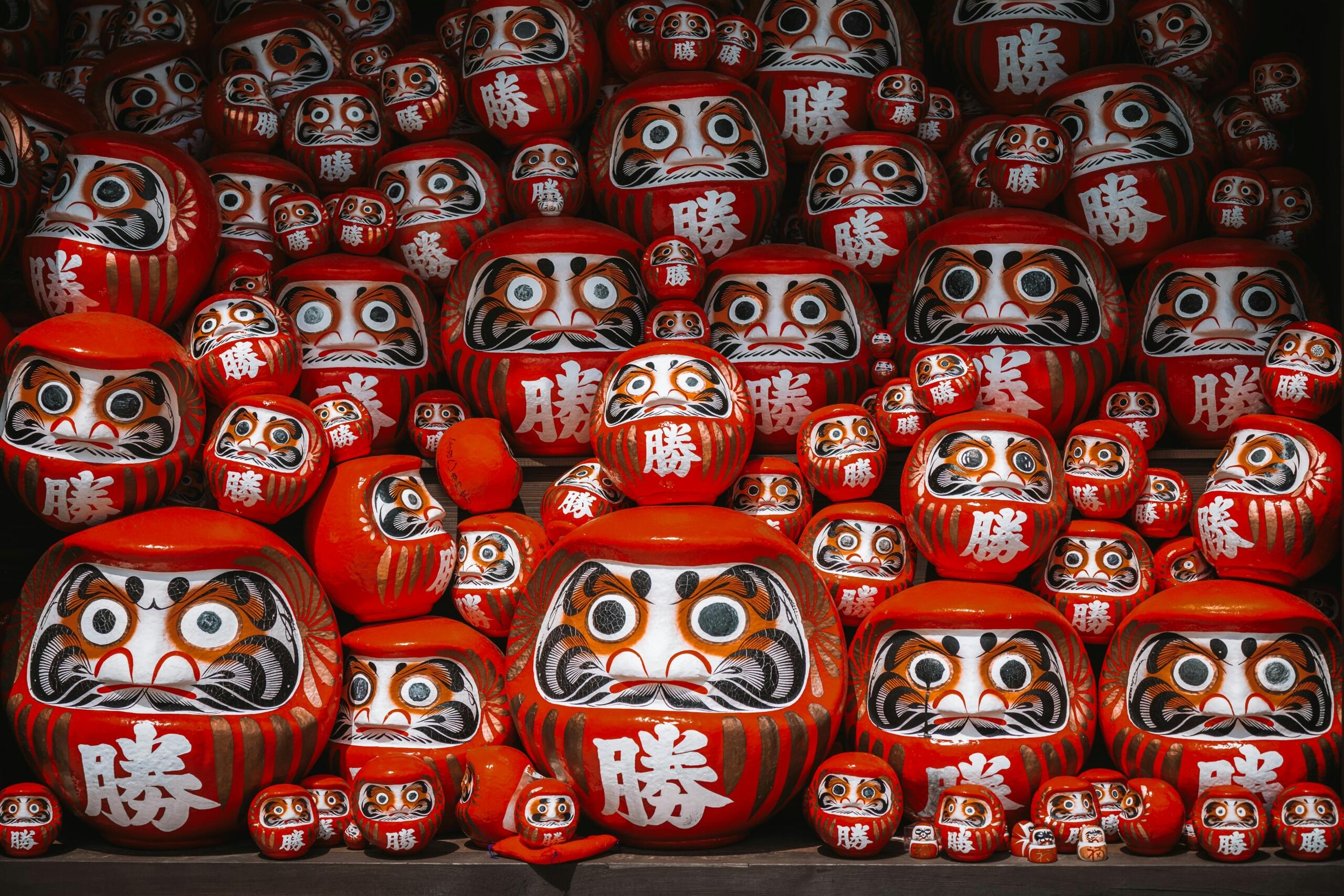 Collection of colorful Daruma dolls with round shapes and painted faces, displayed together as traditional Japanese symbols of luck and perseverance.