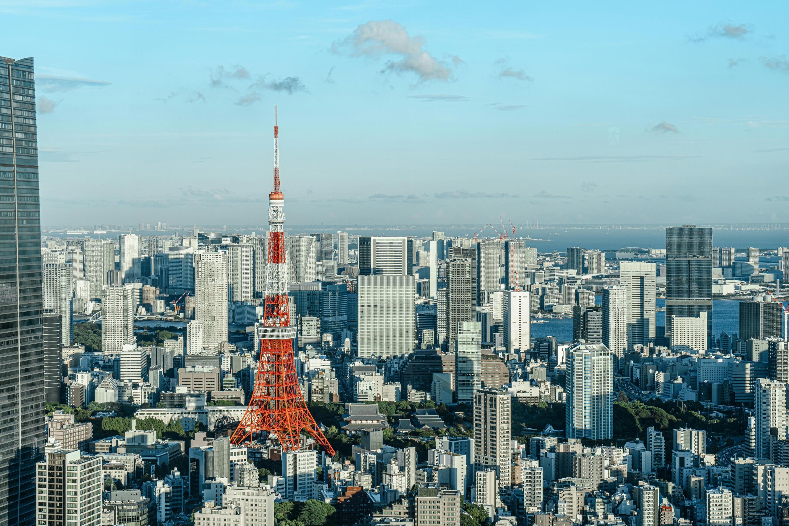 view of the Tokyo skyline with dense clusters of modern skyscrapers, glass office towers, and high-rise apartments stretching across the horizon under a clear sky.