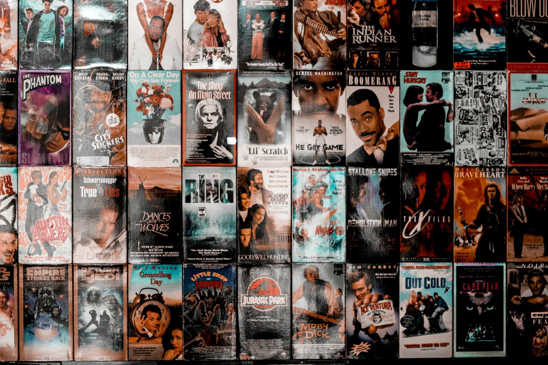 A collage of movie VHS covers featuring various films, showcasing vibrant artwork and iconic titles from different genres.