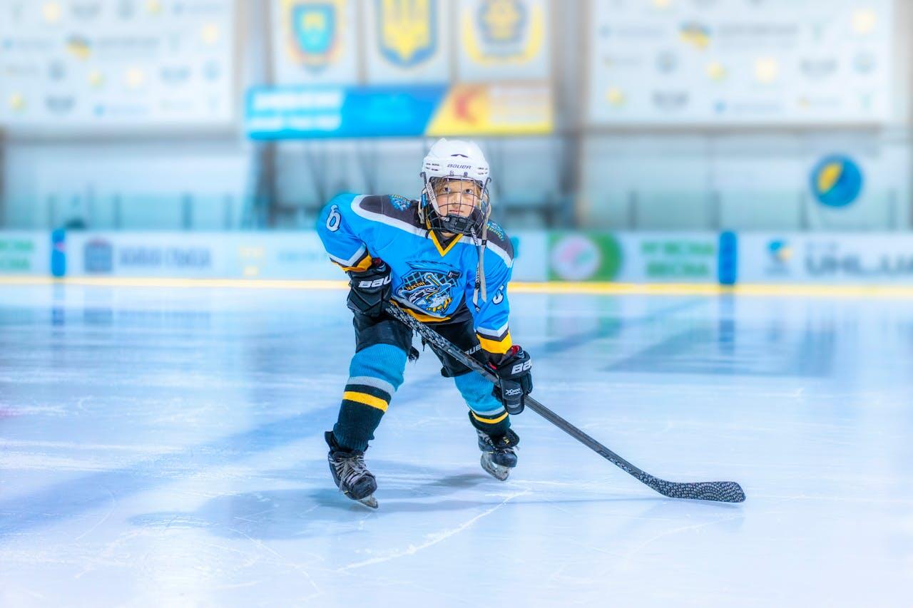 A young hockey player in a blue jersey glides on the ice, holding a stick, ready to make a move during a game.