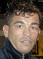 Blurred close-up photo of a person with dark hair wearing a black jacket, with a neutral indoor background.