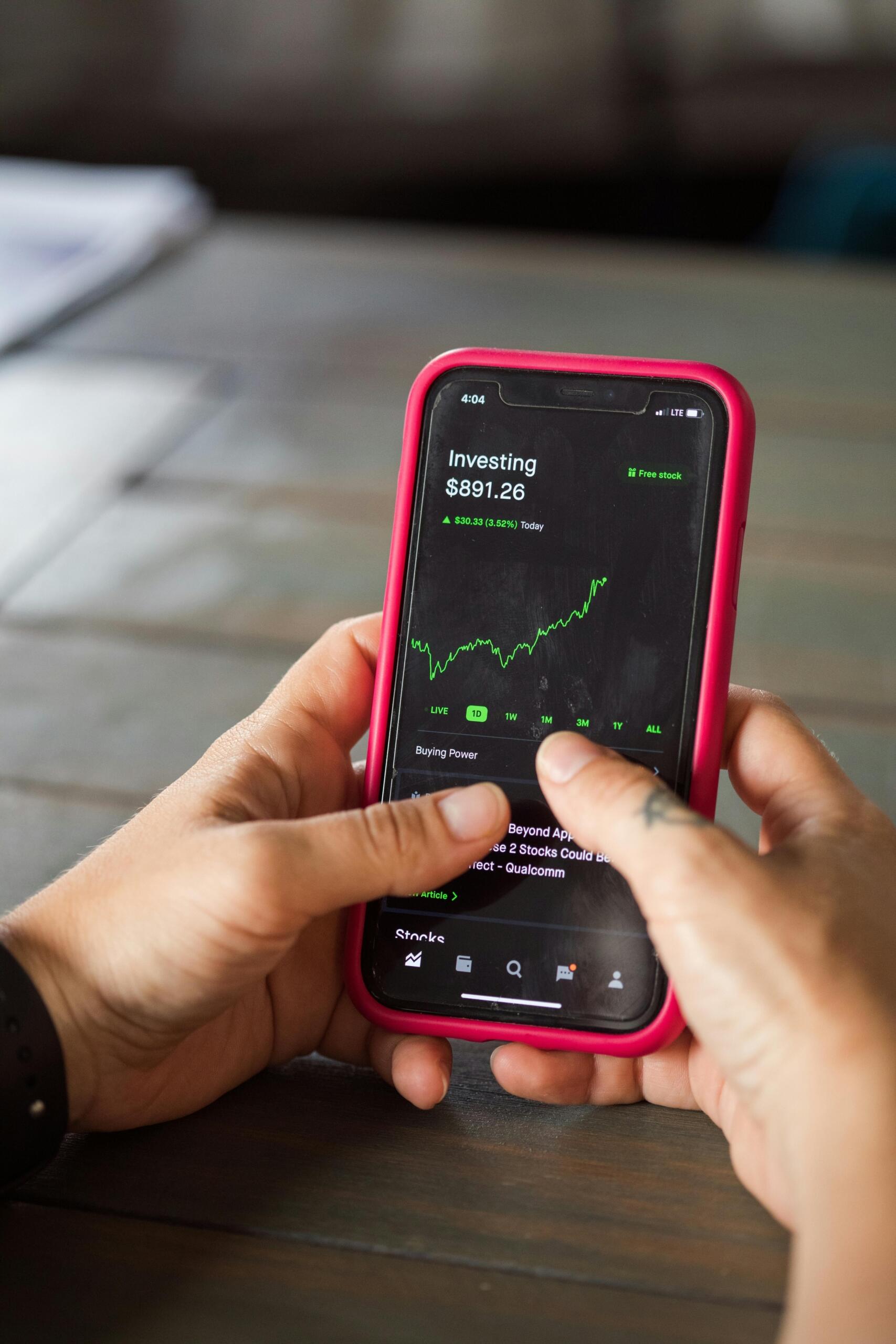 Person using a finance app on a smartphone, reviewing spending, transactions, and account balances on a digital dashboard.
