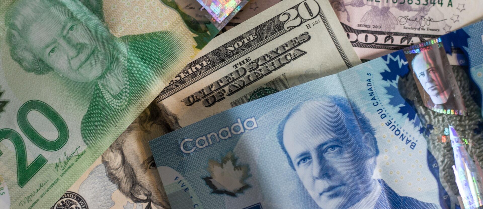 Close-up of layered Canadian, US, and British banknotes featuring portraits and currency details.