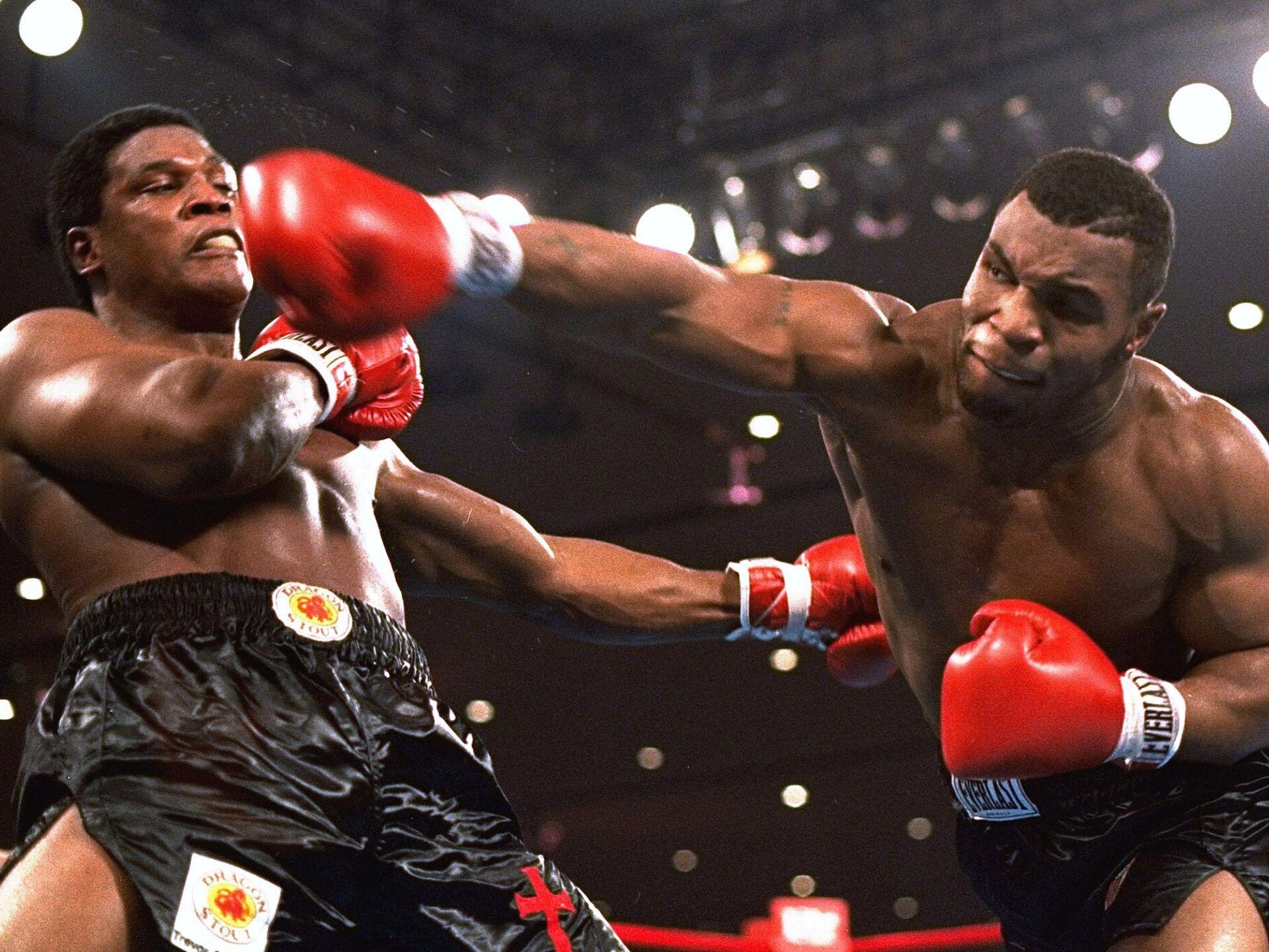 Two professional boxers engage in an intense match, one throwing a powerful punch while the other braces for impact.