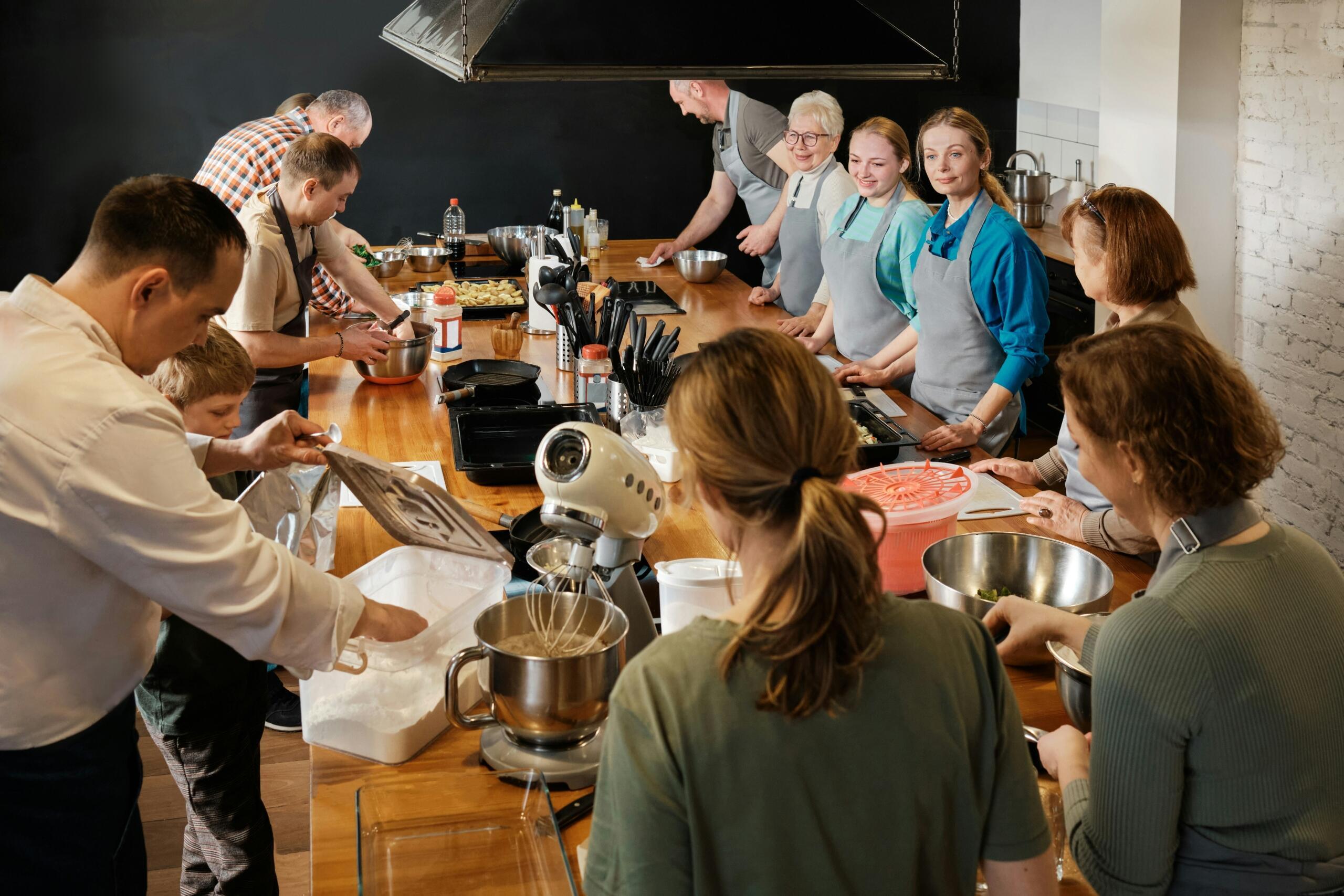 A group of amateur students following cooking instructions from their teacher.